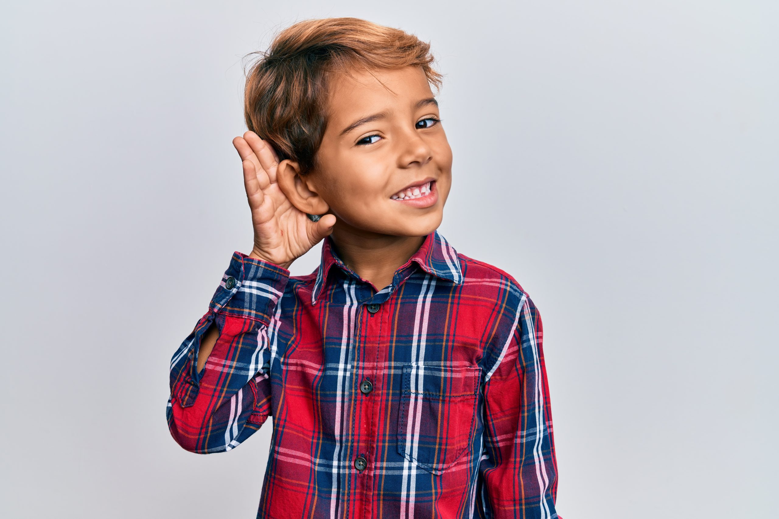 Adorable latin kid wearing casual clothes smiling with hand over ear listening and hearing to rumor or gossip. deafness concept.